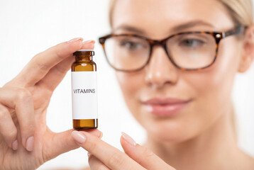 Fototapeta premium Woman with glasses inspects vitamin bottle for health and wellness