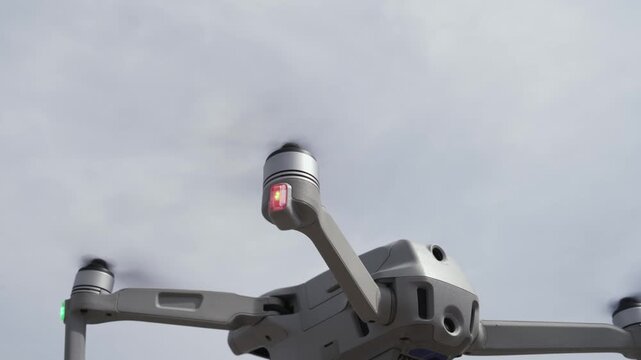 Drone quadcopter with digital camera and fast rotating propellers flying taking video and pictures, slow motion