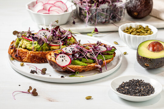 Avocado toast topped with purple radish microgreens, fresh veggies and seeds.