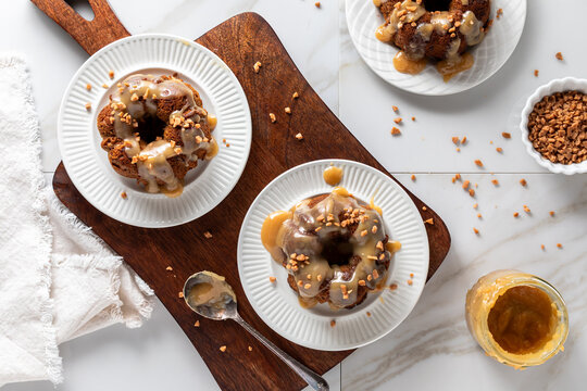 Three servings of sticky toffee pudding desserts topped with caramel sauce.
