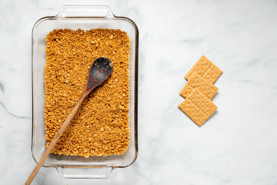 A glass baking dish filled with crushed graham crackers for a layered dessert.