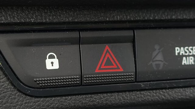 Close up of driver pressing hazard warning button in car, activating emergency signal lights, safety feature in vehicle interior, transportation alert system, dashboard control detail.
