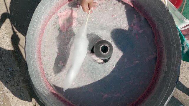 Man making a big pink sugar cloud candy at a fair stall