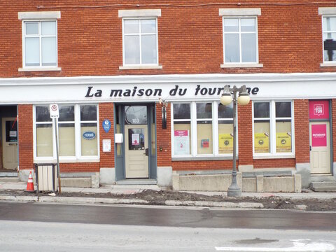 Gatineau, Quebec, Canada &ndash; March 10, 2026: The red brick storefront of "La maison du tourisme" features white signage and informational posters at 103 Rue Laurier.