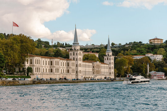 Vista majestuosa de la Academia Kuleli en Estambul con un yate de lujo navegando el B&oacute;sforo. Paisaje ic&oacute;nico del patrimonio hist&oacute;rico turco frente al mar.