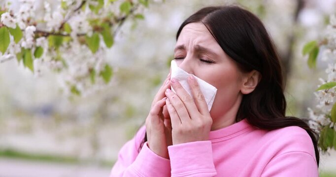 Woman suffering from seasonal allergy in park on spring day