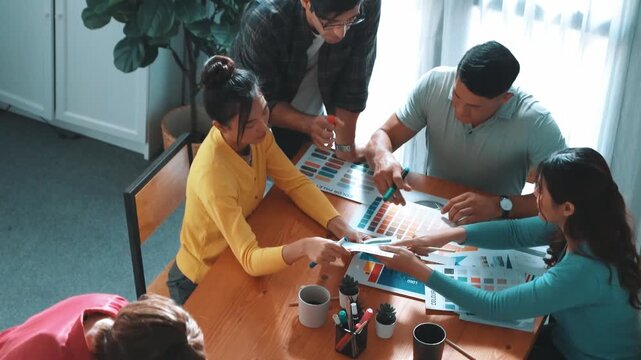 Top view of manager writing idea on sticky notes and explain idea about web design. Professional marketing team or programmer brainstorming idea while looking at tablet with color palette. Symposium.