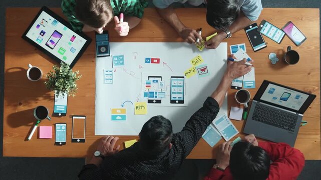 Professional developer team sharing idea of Ux Ui design by using mind map. Top down view of group of business people working together to brainstorm or plan mobile phone interface app. Convocation.