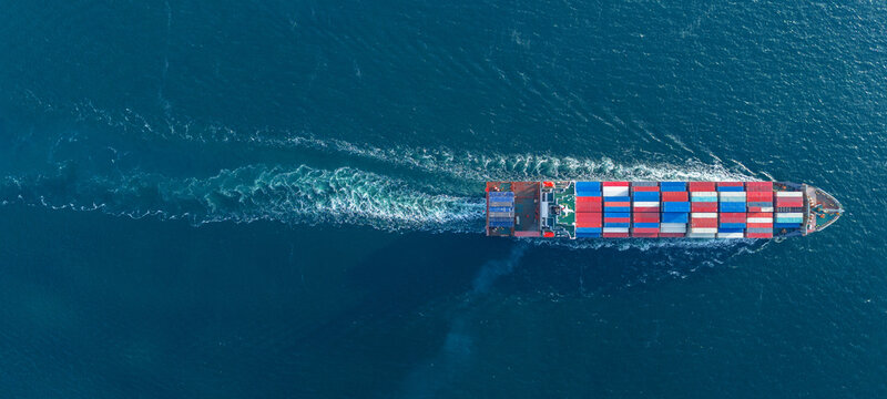 large cargo container ship fully loaded with colorful containers sailing through the deep blue ocean. Global maritime trade, freight transport and logistics business.