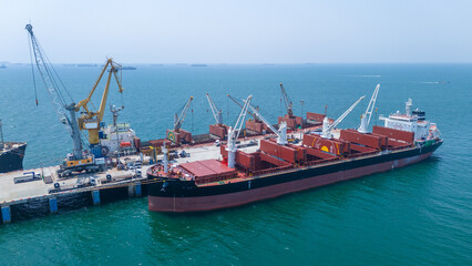 Fototapeta premium a large bulk carrier ship docked at an industrial port terminal for cargo loading. Concept of maritime logistics, global shipping industry, and international trade supply chain.