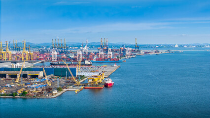 Naklejka premium commercial container port with cargo ships and loading cranes under a blue sky. Ideal blurred backdrop for global logistics, shipping trade, or tech data overlays.