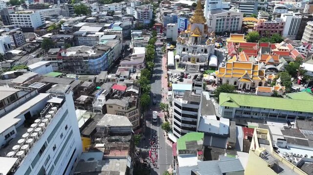 Wat Traimit temple with golden pagoda structure, Temple complex stands within dense city area near Chinatown district.