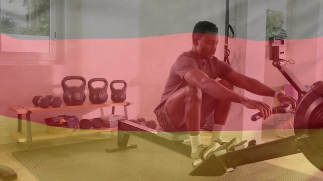 Man using rowing machine performing strokes in gym, initiating drive by pushing legs for fitness