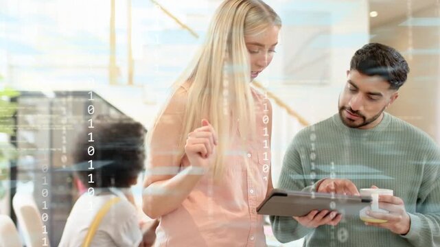 Tech team reviewing tablet, woman showing handing device to man with mug, binary overlaying screen