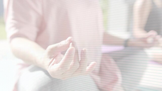 Front woman holding mudra at health session start, background peer mirroring sunlight bathing hand