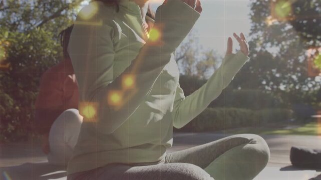 Woman meditating cross-legged, breathing and opening palms while golden bokeh drifting over hands