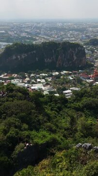 Vertical screen, Vietnam, Da Nang, Marble Mountains Rows Of Houses Clustered At Cliff Base With Dramatic Vertical Rock Face Beyond, Narrow Streets And Dense Rooftops, Market Stalls