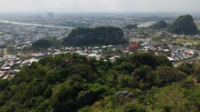Vietnam, Da Nang, Marble Mountains Red Temple And Dense Rooftops Below Cliff, Riverside Town Spread Across Valley, Winding Roads And Market Streets Visible, Cultural Architecture