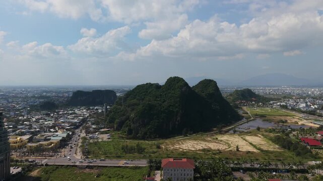 Vietnam, Da Nang, Marble Mountains Karst Hills Rising Above Rural Plain With Dense Vegetation And Winding Road, Aerial View Of Marble Mountain Cluster, Distant City And Hazy Horizon