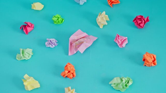 Stop motion of Pink sticky note with messy scribble sits center colorful crumpled papers