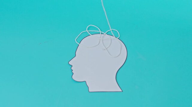 White paper head silhouette slowly fills with tangled white thread on blue background for mental clutter and ADHD Concept
