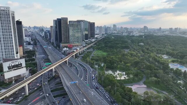Lat Phrao intersection with multiple elevated roads, highway layers crossing urban buildings. Curved complex transportation structure.