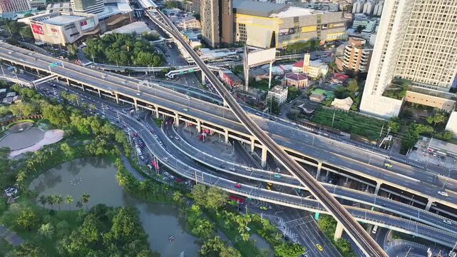Lat Phrao intersection with multiple elevated roads, highway layers crossing urban buildings. Curved complex transportation structure.