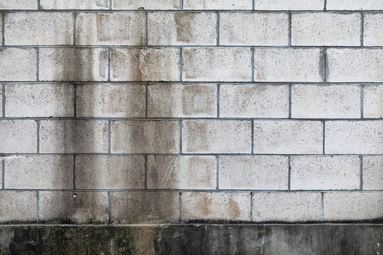 Light grey concrete block wall with dark vertical moisture stains