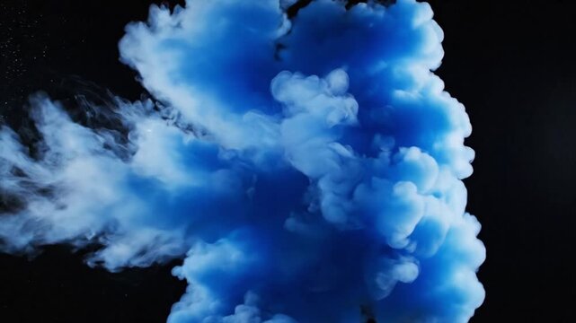Blue ink cloud expanding in water on black background