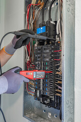 Electrician testing a dual-function smart breaker in an electrical panel with a voltage tester, USA © Andrei Liashchou