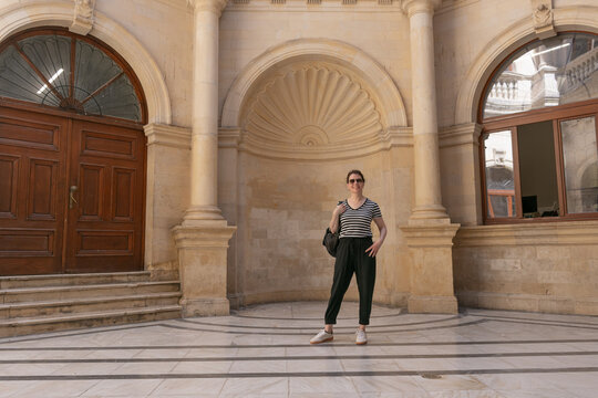 Turista en el patio interior de la Logia de Heracli&oacute;n, Creta, edificio hist&oacute;rico de arquitectura veneciana. Espacio cl&aacute;sico con arcos, columnas y suelos de m&aacute;rmol.