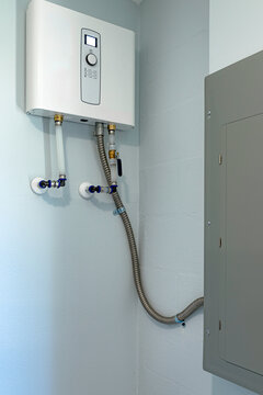 Tankless electric water heater installed on a wall next to an electrical panel, USA