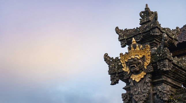 Ancient Balinese Hindu Temple Guardian Bhoma Statue with Gold Ornaments and Twilight Sky Copy Space