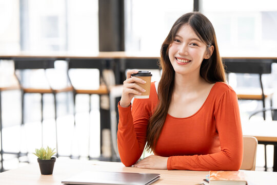 Beautiful Asian Woman Smiling at Camera While Holding Coffee in Cafe