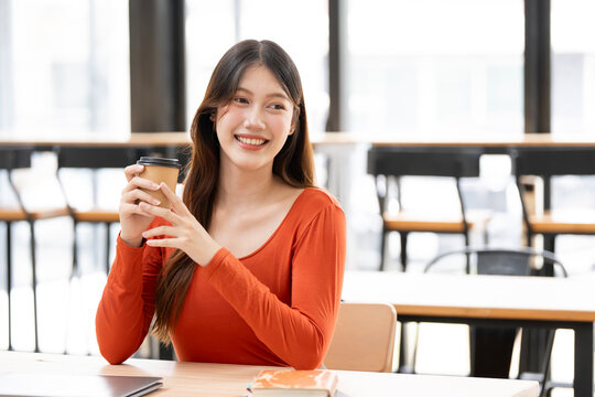 Happy Young Asian Woman Enjoying Coffee Break in Modern Cafe Workspace