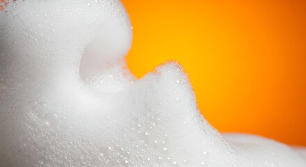 Fototapeta premium Close-up of White Foam Bubbles Against a Vibrant Orange Background.