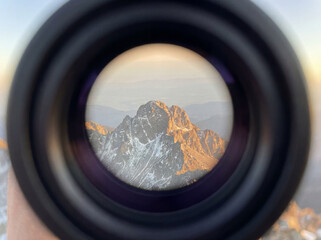Naklejka premium POV through a telescope blurred edges focusing on a distant mountain peak touched by light