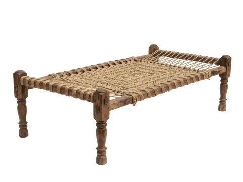 Rustic woven charpai bed with carved wooden legs, isolated on a white background, showcasing traditional indian craftsmanship in a neutral, earthy tone.