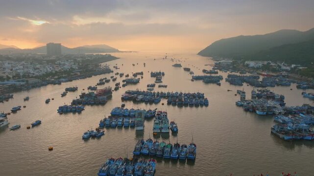 A vast fleet of fishing boats are docked in a harbor at sunrise in Nha Trang, Vietnam. The boats are preparing for a day of fishing.