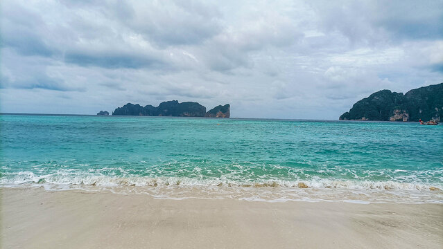 Phi Phi Island on August 15, 2025: Tropical sea waves crashing white sand beach under clouds