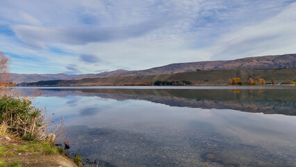 Obraz premium Serene Autumn Landscape of Lake Dunstan with Mountain Reflections in New Zealand