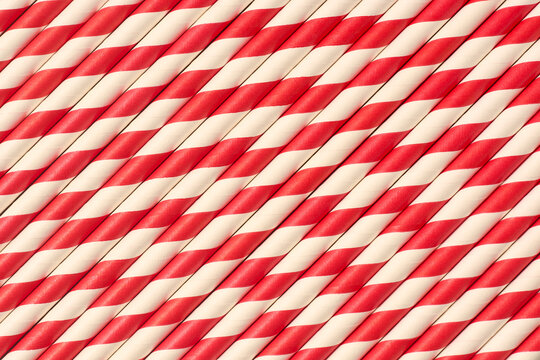 red and white striped paper straws in diagonal pattern, matte finish drink accessories in full frame texture, top view of party supply background concept
