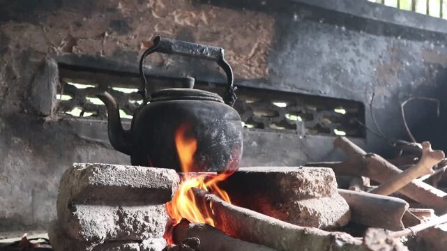 boiling water with an old kettle on a wood stove in a rural area of Java, Indonesia, at a kitchen in a rural area in Indonesia, an old kettle to boil water on a traditional stove, a traditional stove 