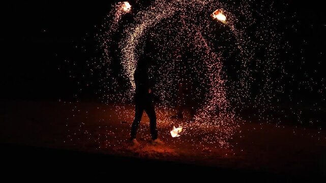 Dynamic fire spinner creates mesmerizing trails of sparks at night, performing spectacular light show.