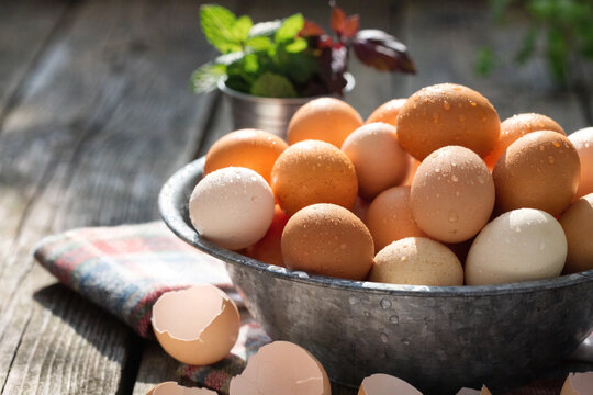Fresh brown eggs in a metal bowl on a wooden table