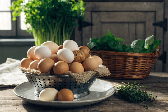 Fresh chicken eggs in a metal colander on a rustic table