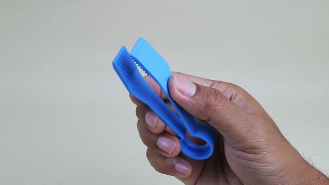 Hand opening and closing blue plastic clamp tool close up