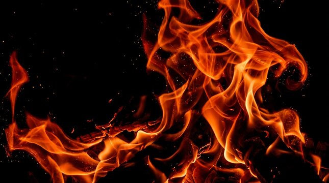 Vibrant orange fire flames with glowing embers dancing against a dramatic black background, representing passion, energy, intense heat, and primal power for conceptual designs.