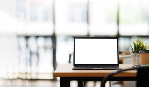 Modern Laptop with Blank Screen on Wooden Desk in Bright Blurred Cafe Interior &ndash; Mockup Template