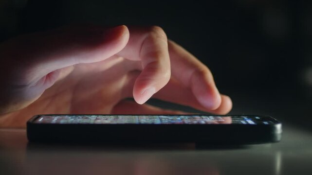 Smartphone social media scrolling by male hand shows modern digital lifestyle and fast online connection at night. Smartphone screen glow reflects daily communication habits positive mobile engagement